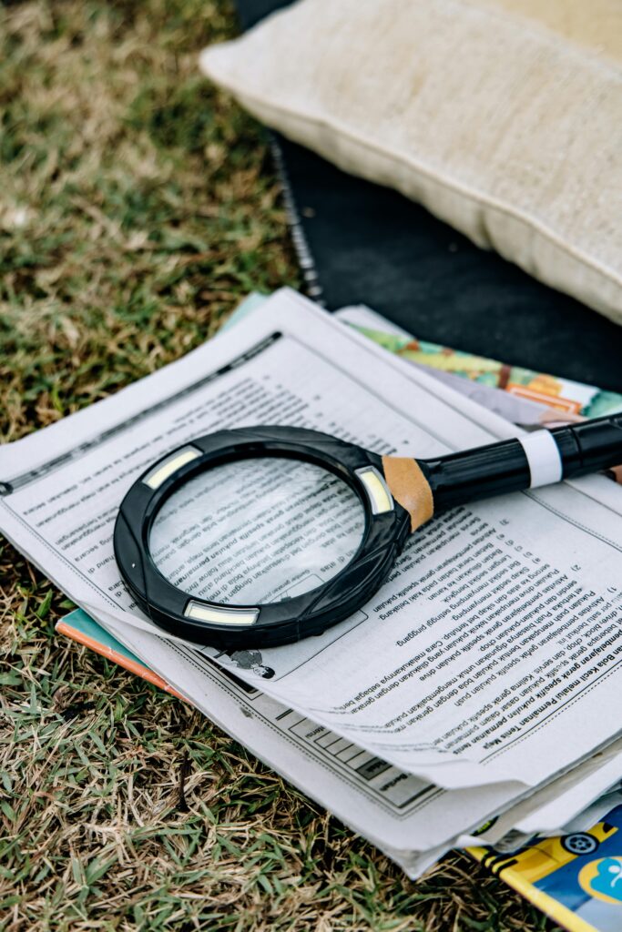pexels-photo-12719256-12719256 A magnifying glass rests on papers outdoors, suggesting research or reading.
